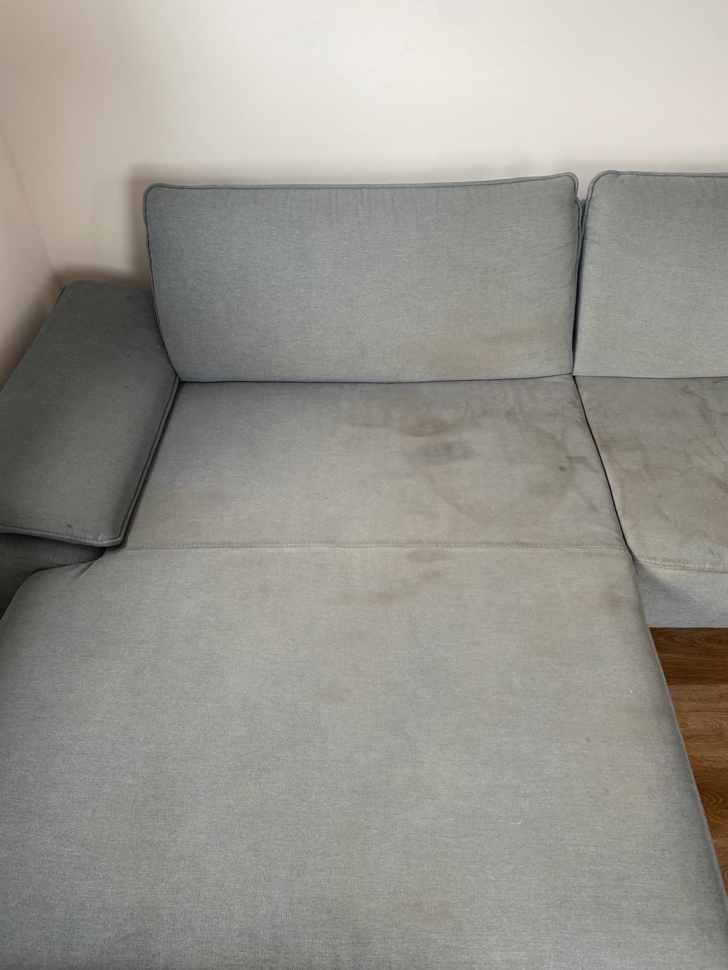 Verschmutztes graues Stoff-Ecksofa vor der Polsterreinigung